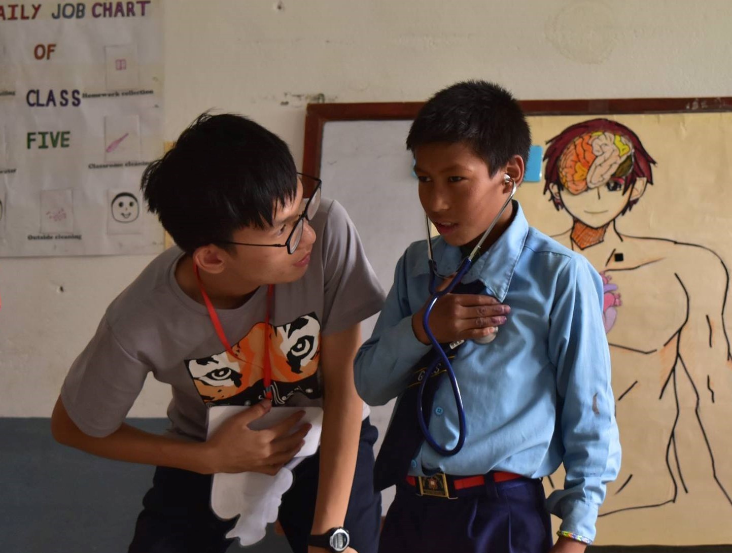 國防(尼泊爾)團員謝士博正在進行衛教課程，讓學童聽自己的心跳聲，協助認識身體器官。