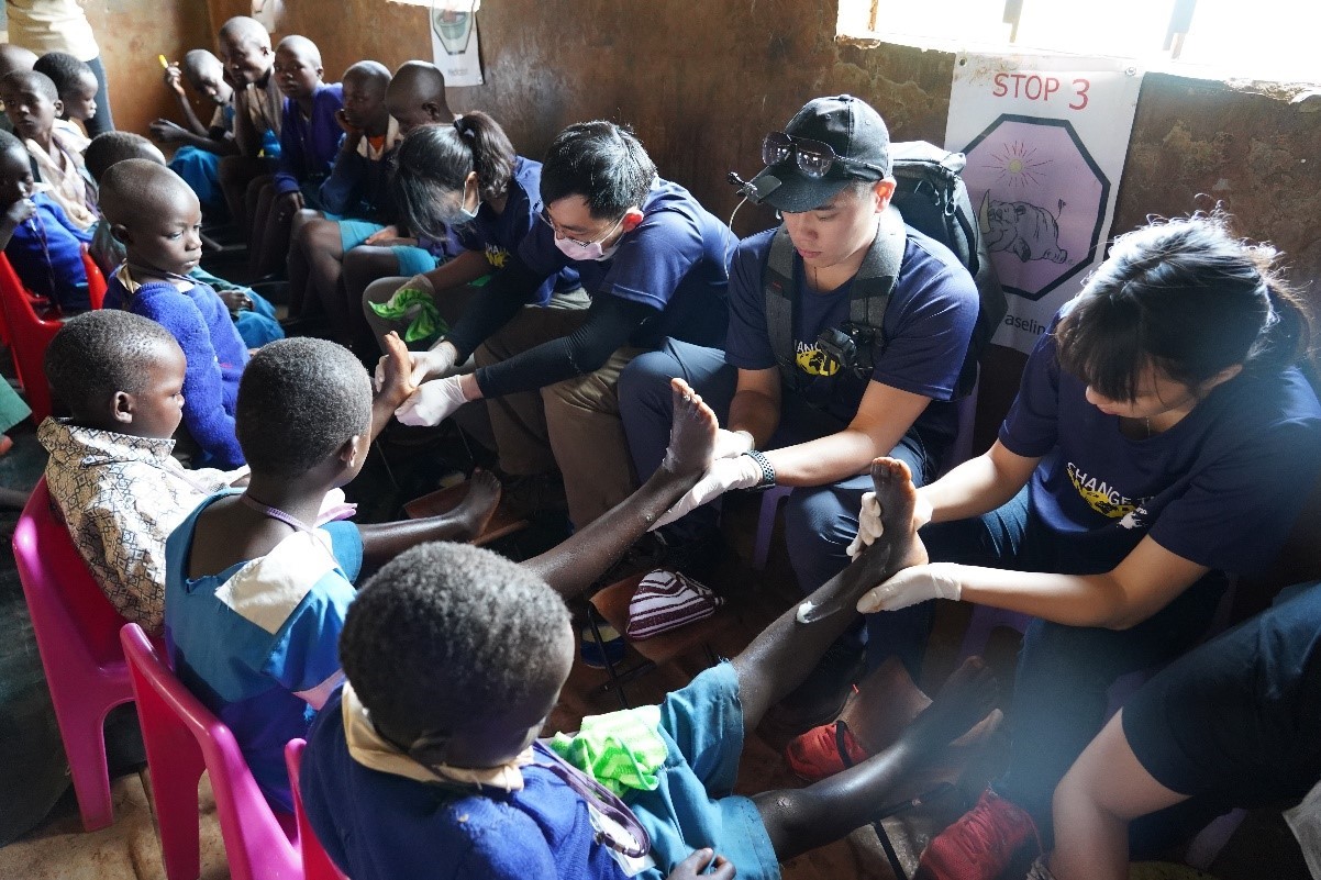 照片二：團員幫當地學童洗完腳泡過藥後，在學童的腳上塗上凡士林。